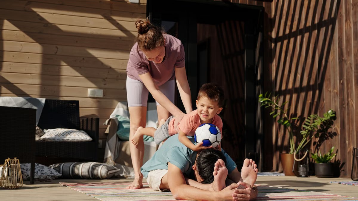 Family engaging in playful yoga on a sunlit porch, bonding and exercising together.